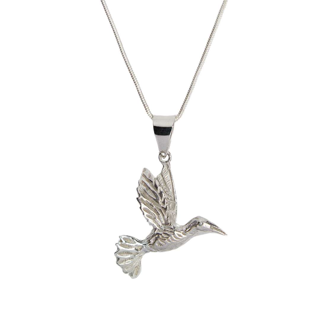 The Wildlife Pendant - Bird In Flight With Chain by Watermelon Tropical is a striking silver necklace featuring a detailed hummingbird in flight, outstretched wings, and long beak—an elegant nature-inspired accessory.