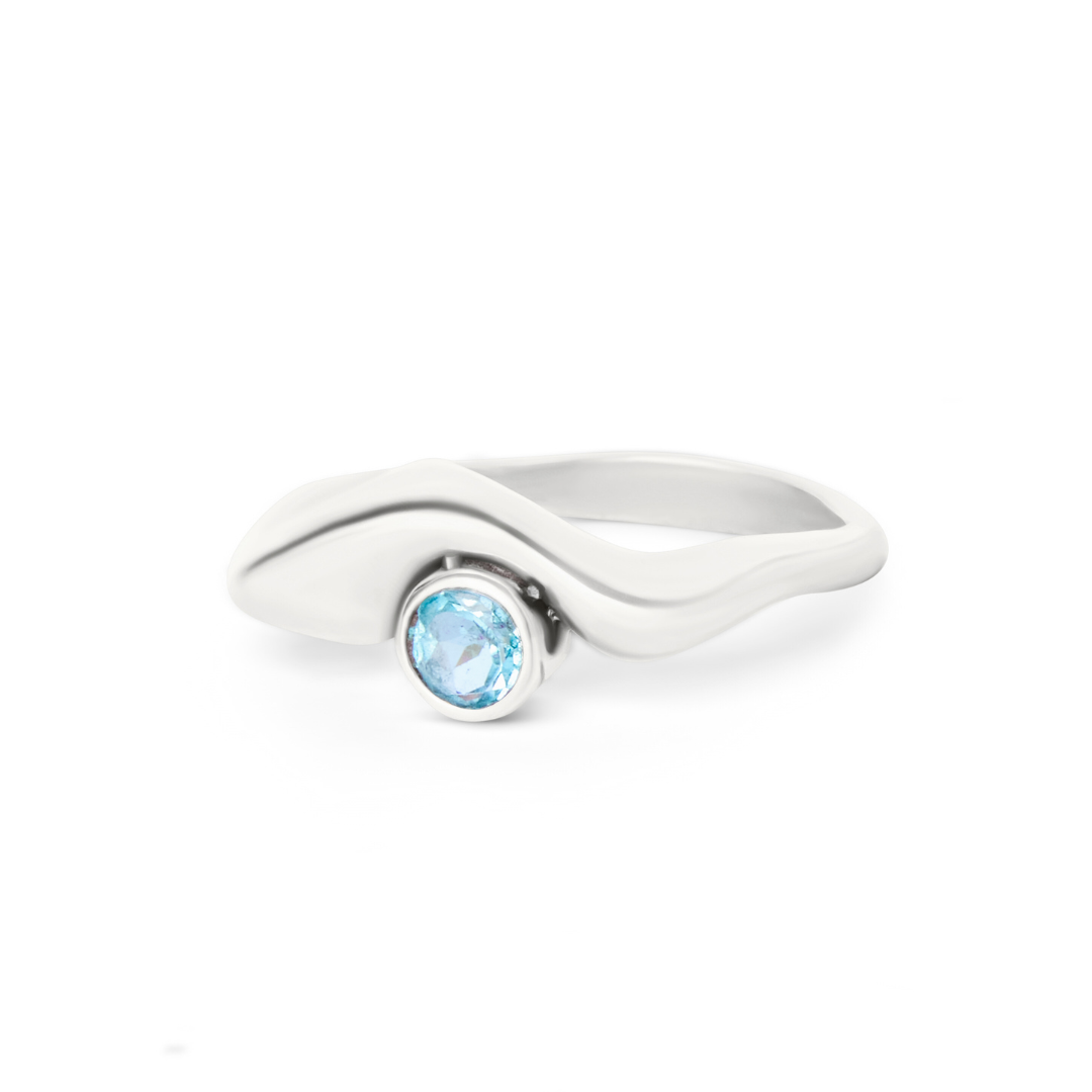 The Bough Ring Blue Topaz by Madeleine Sculptural Jewellery is a handmade silver ring with a wavy, organic design and a central round blue topaz in a smooth bezel setting, inspired by nature.