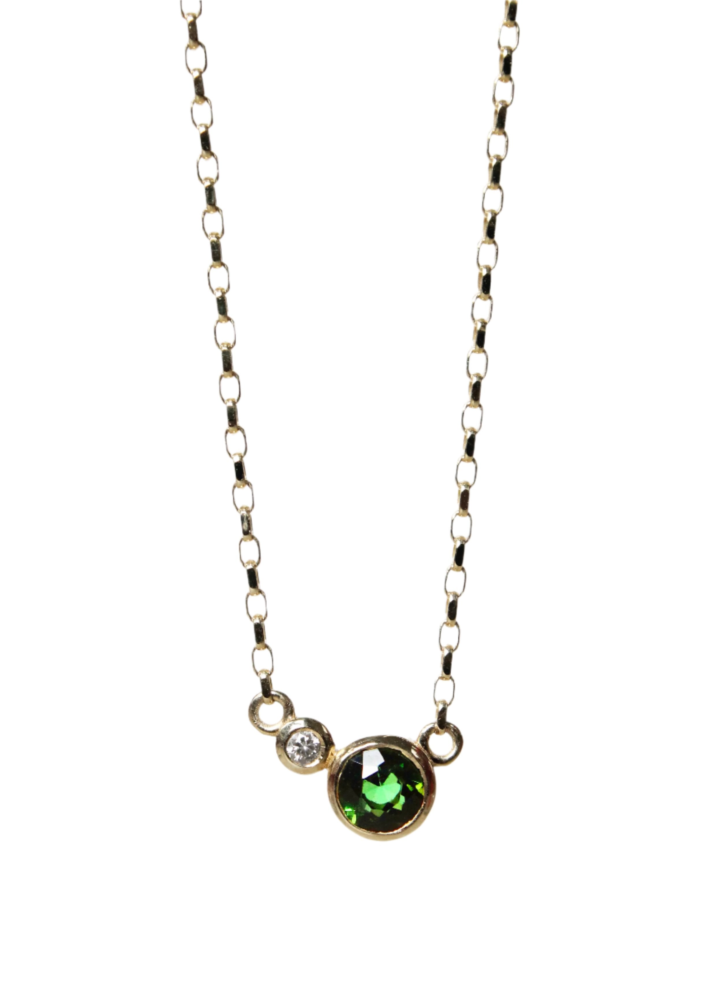 The Verdant Embrace 9ct Yellow Gold Necklace by Madeleine Fine Jewellery features a delicate chain with a small round green tourmaline and a petite lab-grown diamond set side by side in simple yellow gold.