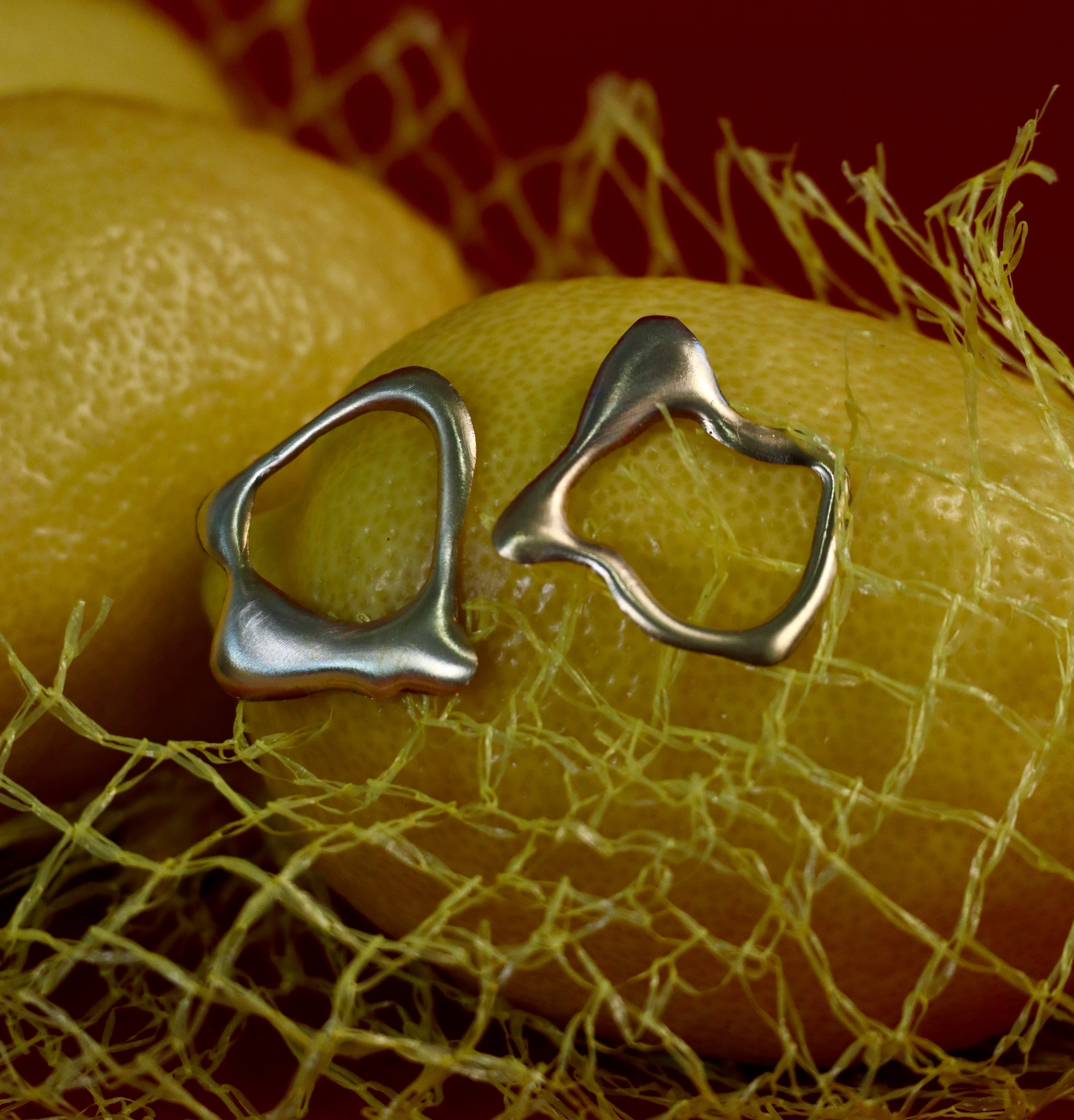 Asymmetrical Molten Studs by Madeleine Sculptural Jewellery, echoing the fresh allure of lemons in a net and inspired by handmade jewellery and organic designs.