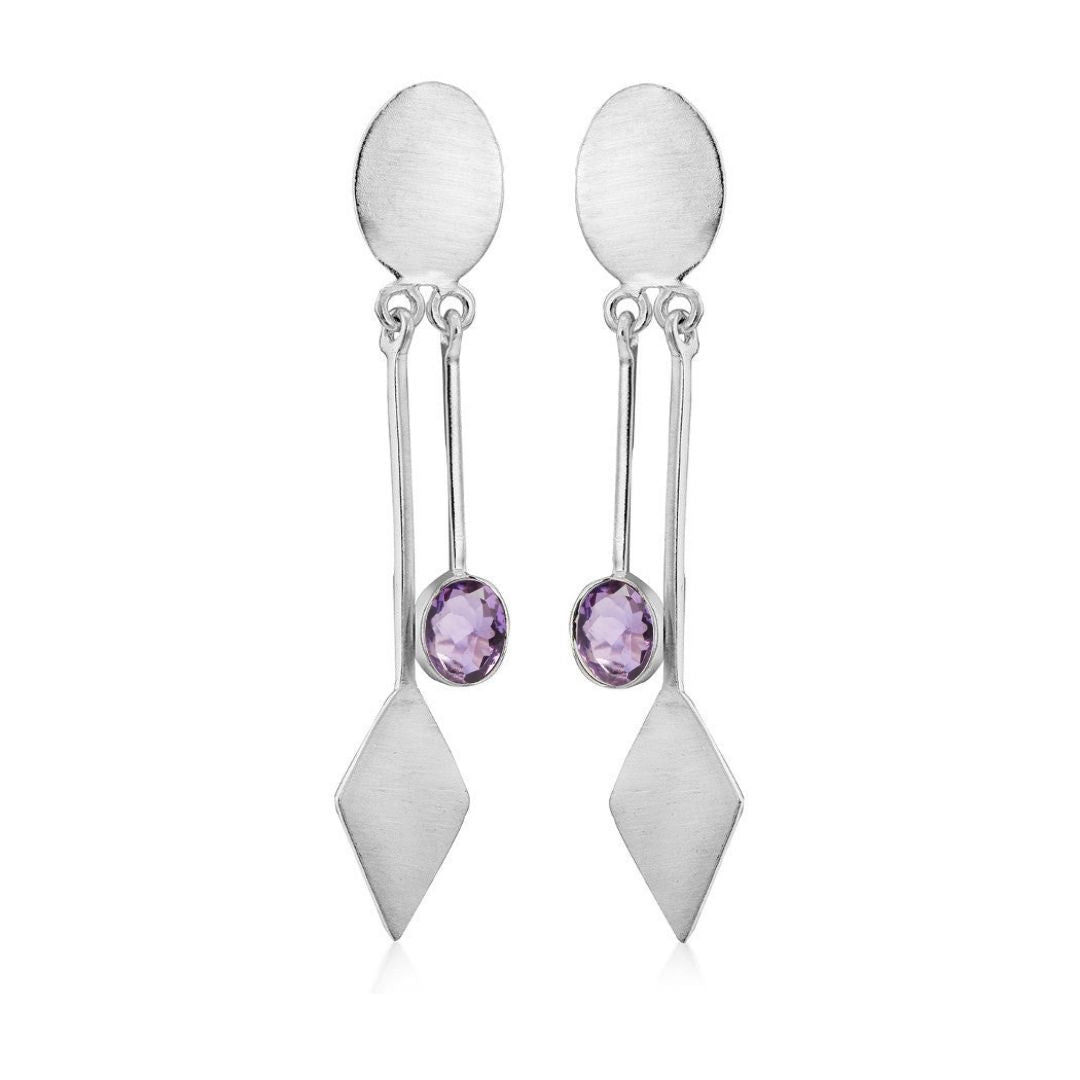 Introducing Gallardo & Blaine Designs' Karo Earrings, a blend of modern elegance and timeless style. These silver dangle drop earrings feature an oval top, a long vertical bar with a diamond shape at the bottom, and centrally set round purple gemstones.