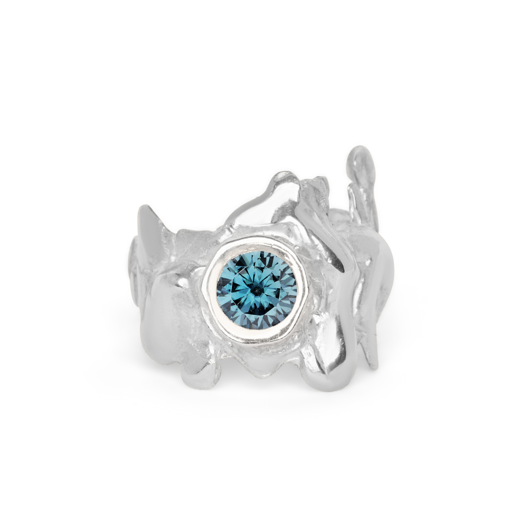 The Solstice Ring with Large Moissanite by Madeleine Blaine features an abstract, organic silver design accented with a striking round moissanite at its center, showcasing the artistry of custom-made jewelry for those seeking truly unique pieces.