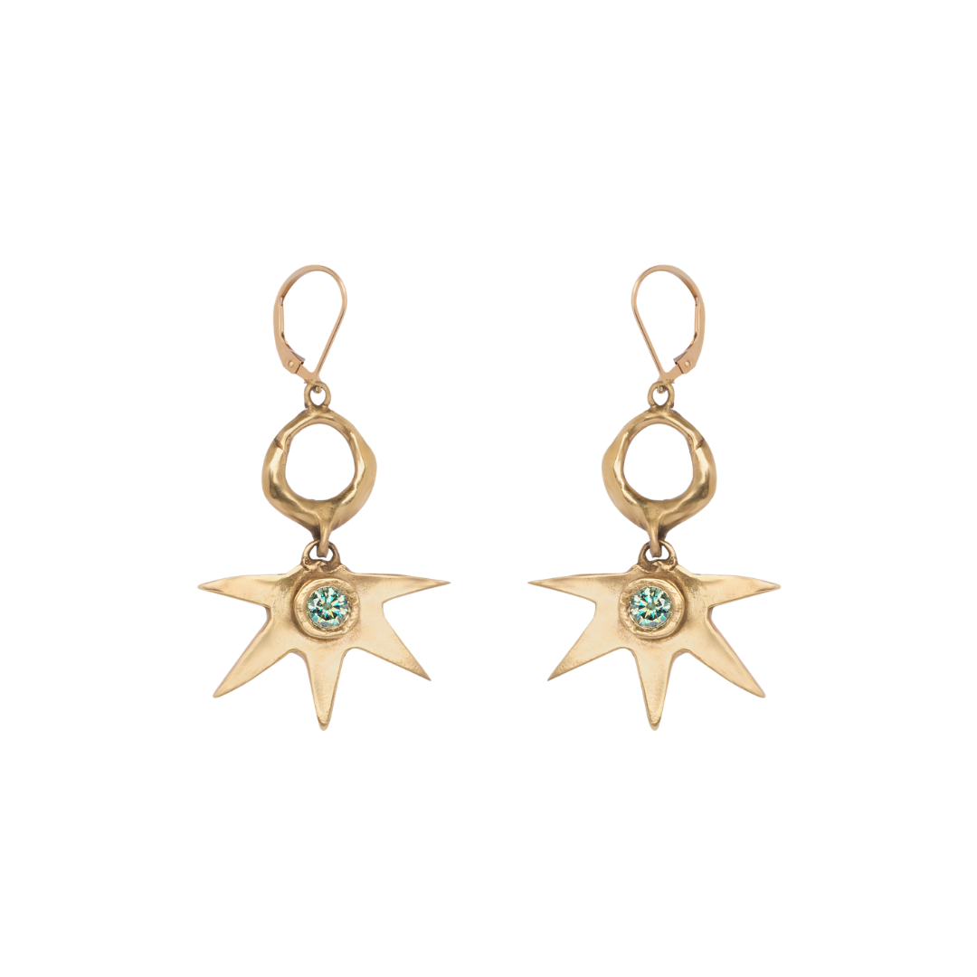 Introducing the Réalta Earrings with 1 Moissanite by Madeleine Blaine: gold, star-shaped dangle earrings featuring a vibrant green moissanite gemstone at the center. Each earring hangs gracefully from a small open circle and is secured with a lever-back h