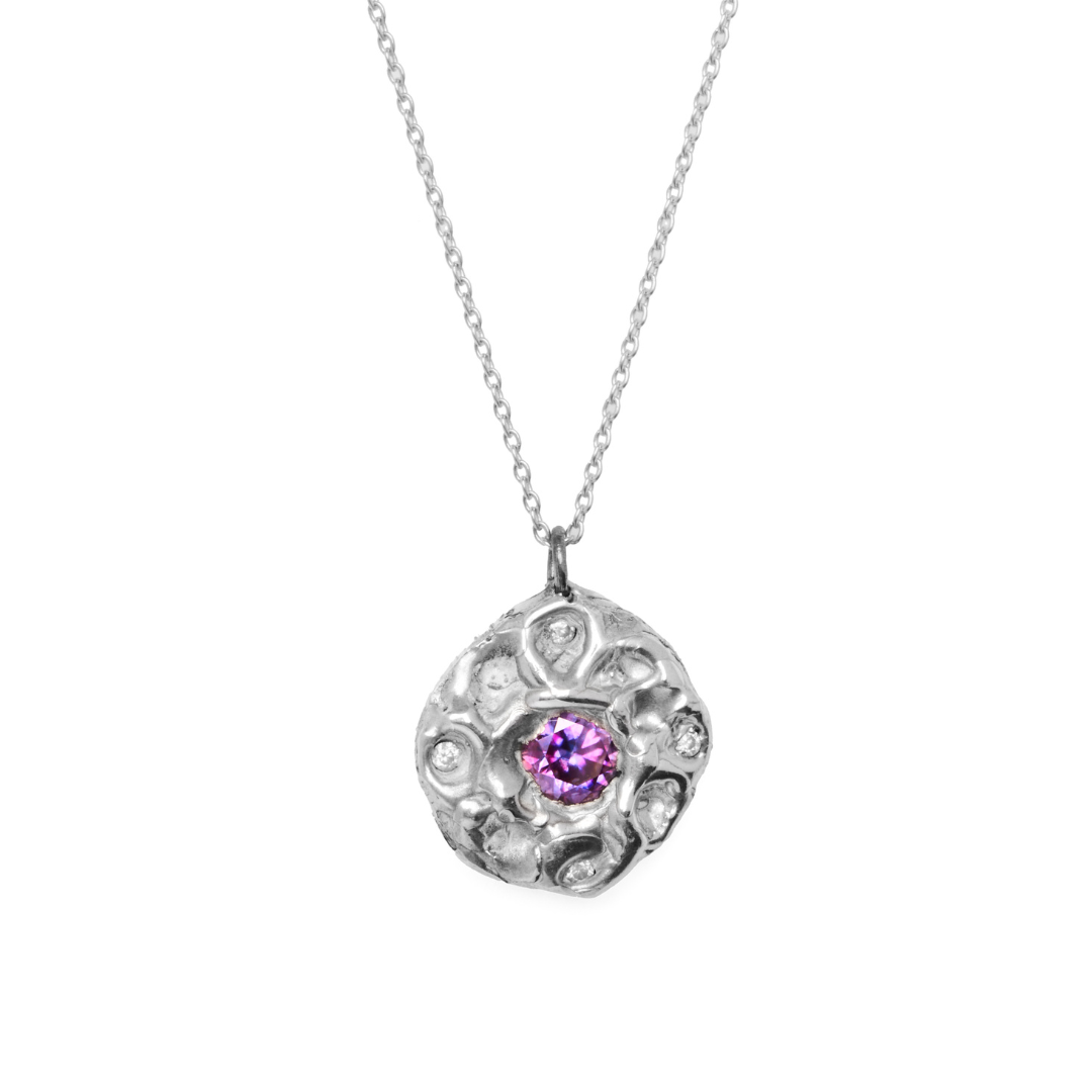 A Multi Stone Moissanite Silver Necklace by Madeleine Sculptural Jewellery, featuring a textured round pendant with a central purple gemstone and shimmering lab-grown moissanite accents.