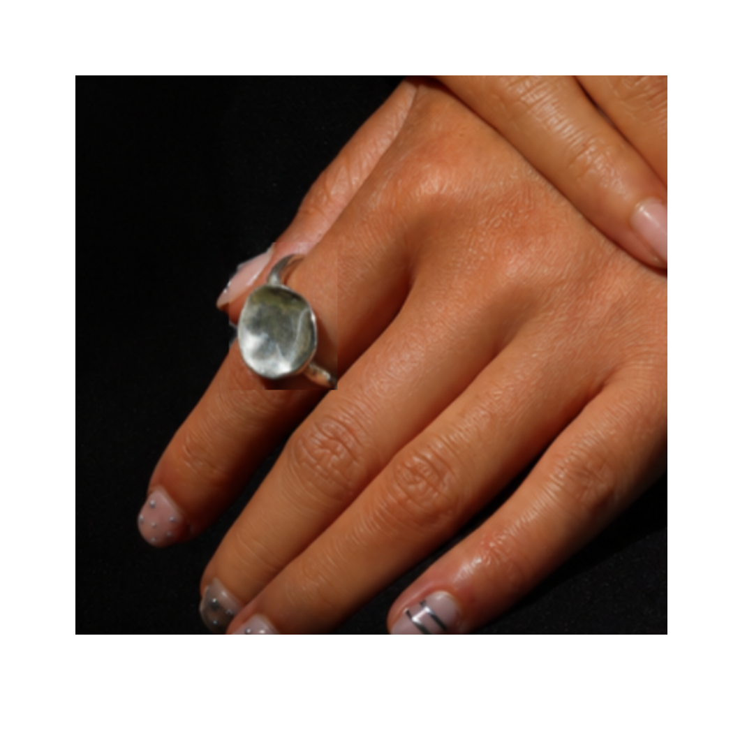 A hand with painted nails wears the large, oval silver Tide Ring by Madeleine Sculptural Jewellery on the middle finger against a black background, highlighting the elegance of this Irish jewelry piece, hand-carved in Dublin.