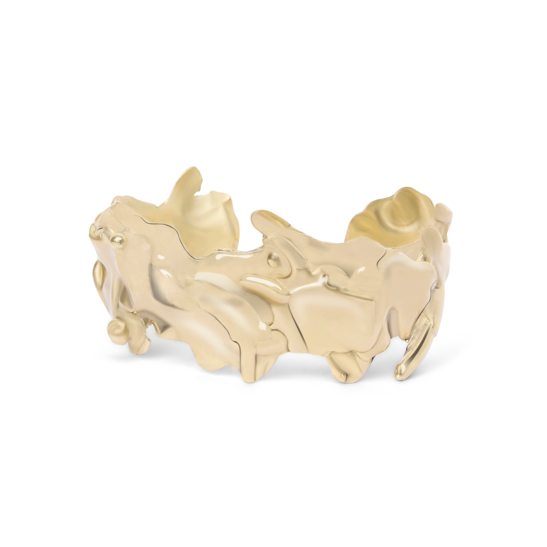 Introducing the Molten Cuff by Madeleine Blaine—a gold cuff bracelet showcasing an abstract, organic, and textured design with uneven, wavy edges and a lustrous finish. Inspired by hand-carved jewelry traditions in Dublin, this stunning piece is a true st