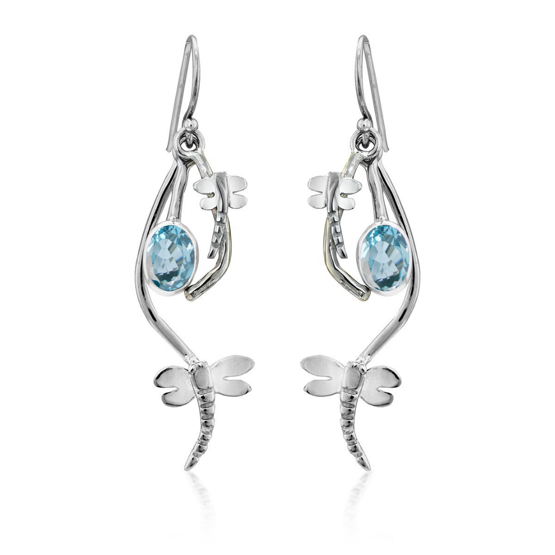 Ripple Earrings by Gallardo & Blaine Designs feature dragonfly-shaped sterling silver with light blue oval gemstones at the center. These elegant earrings have a polished finish and dangle from hooks.