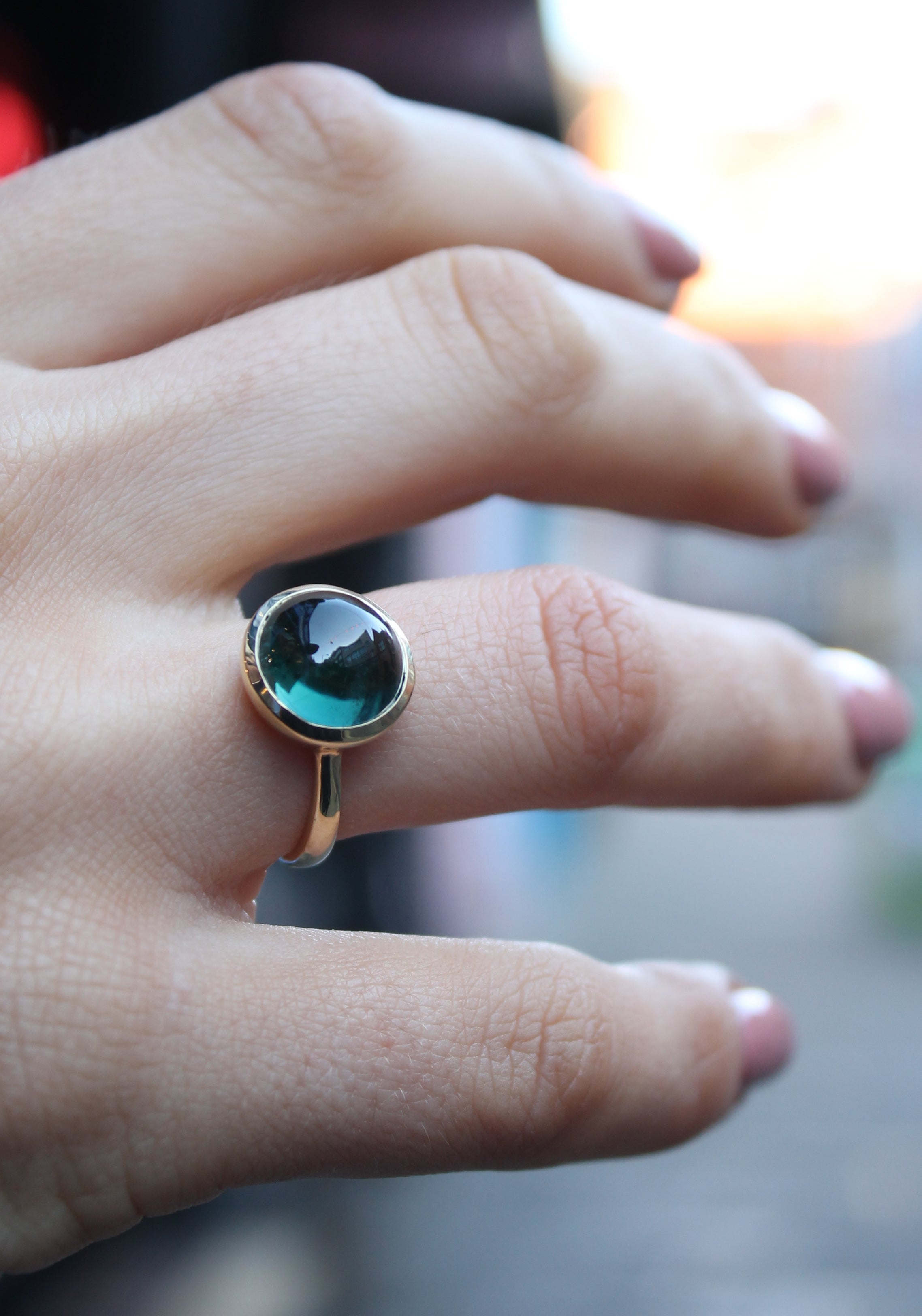 9ct yellow gold ring with a round dark green tourmaline cabochon in a bezel setting. The 9ct yellow gold band is D shaped widest at the back at 3mm wide. Shown here on a ring finger.