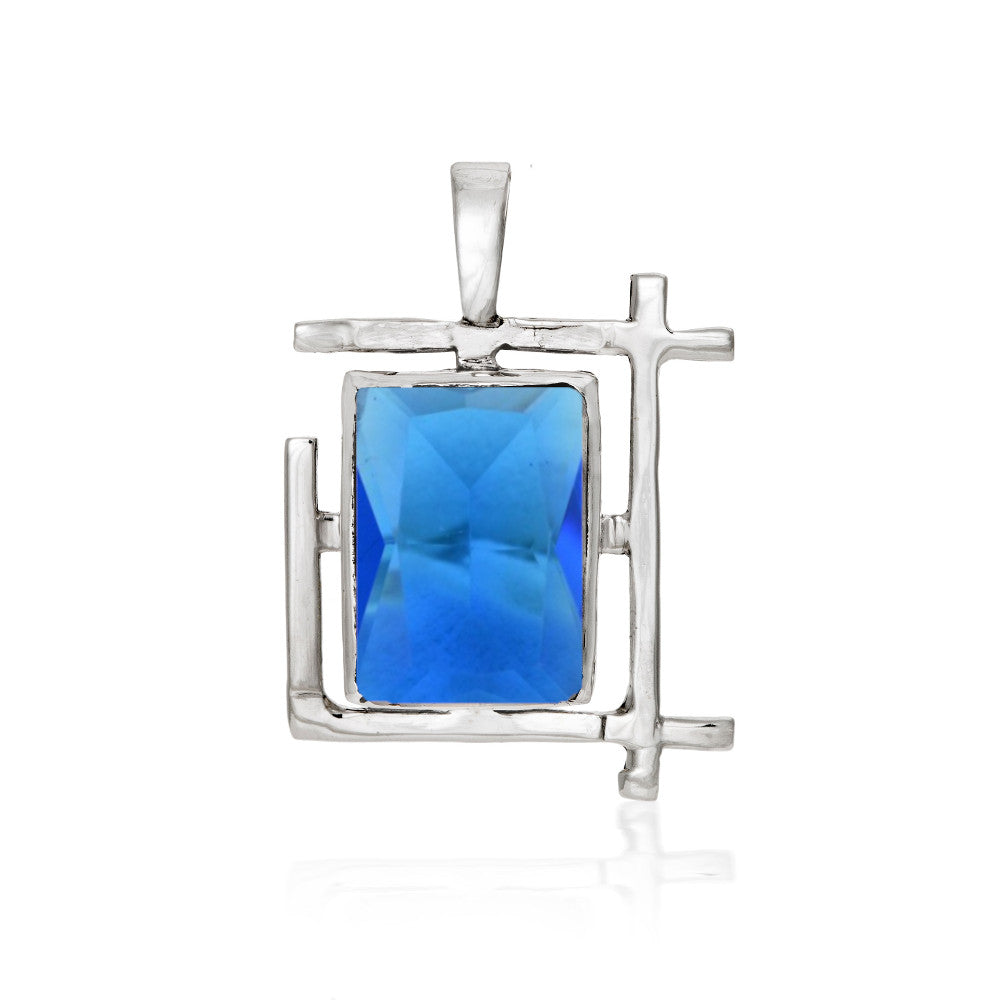 The Art Deco Pendant in various gemstones by Gallardo & Blaine Designs is a rectangular sterling silver pendant with an abstract design, featuring a prominent blue rectangular gem at the center. The silver frame has geometric, angled lines, reminiscent of