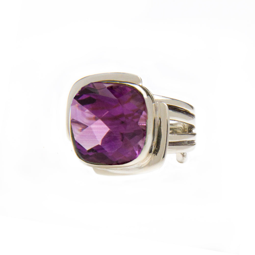 A sterling silver ring featuring a large, square-cut purple gemstone with a faceted surface. The band has a split design, adding to its intricate and elegant appearance reminiscent of an Art Deco ring. Displayed against a plain white background, this piec
