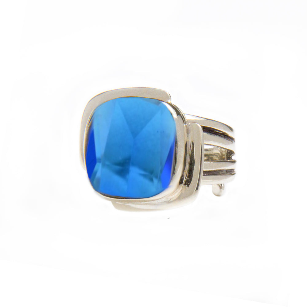 A sterling silver ring featuring a large, faceted blue gemstone. The band has a sleek, modern design with multiple loops for a contemporary look. The square-cut gemstone adds a bold and elegant touch to this Art Deco Ring in Silver Gold & various gemstone