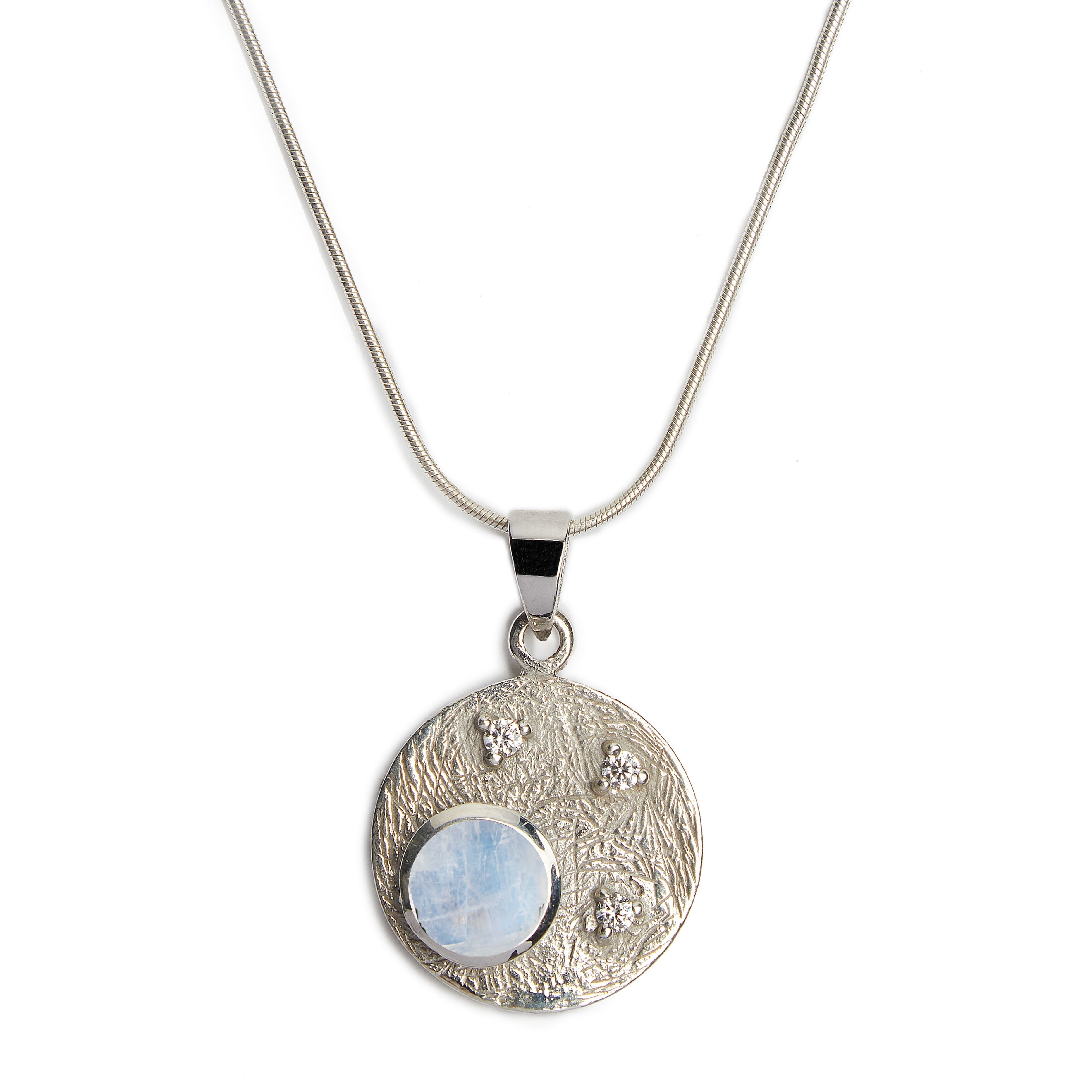 Introducing the Celeste Necklace in Silver & various gemstones by Gallardo & Blaine Designs, a sterling silver pendant necklace featuring a round, textured disc with a polished finish. The disc displays a translucent blue gemstone and three smaller sparkl