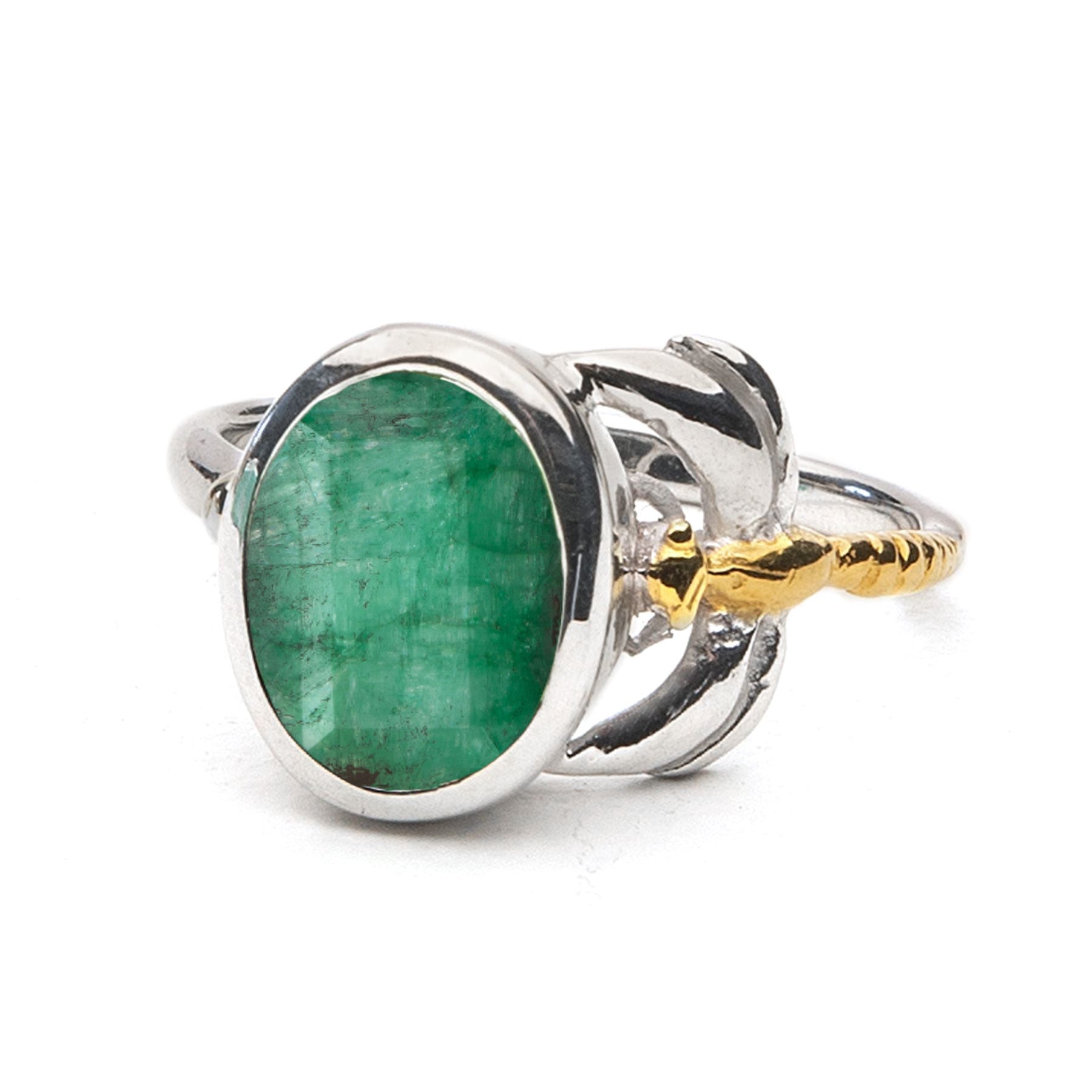 A Daydream Ring in various gemstones featuring a large, oval-shaped green gemstone set in the center by Gallardo & Blaine Designs. This timeless piece boasts intricate design elements, including a gold-toned accent on one side. The band has smooth, polish