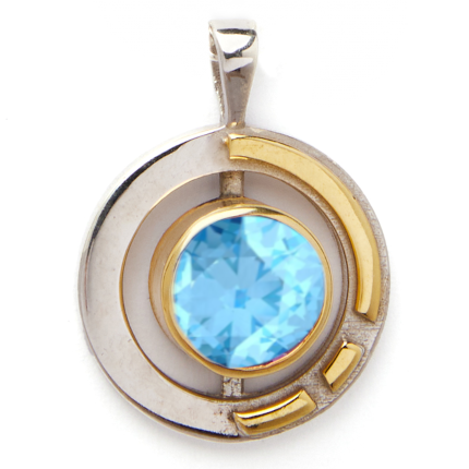 The Elodie Pendant in silver gold & various gemstones by Gallardo & Blaine Designs features a large, round, faceted blue gemstone at its center. Crafted from sterling silver and gold vermeil, the circular design incorporates two gold curved accents framin