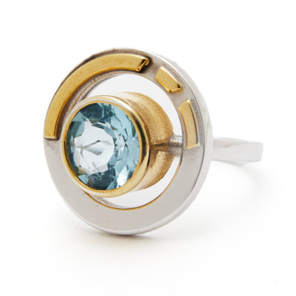 Introducing the Elodie Ring in Silver Gold & various gemstones by Gallardo & Blaine Designs: a modern piece featuring a circular design and a central light blue gemstone set in gold. This ring also incorporates silver and gold details, effortlessly blendi