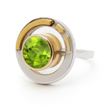 The Elodie Ring in Silver Gold & various gemstones by Gallardo & Blaine Designs is a perfect blend of vintage style glamour and modern design, featuring a bright green gemstone set in the center of a round, two-toned band. The primarily silver band with g