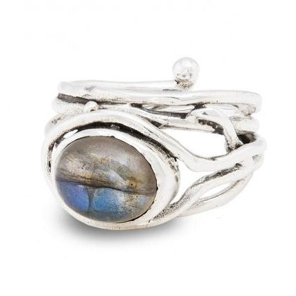A Fossil Ring in silver & various gemstones featuring an oval labradorite gemstone with iridescent blue and grey hues by Gallardo & Blaine Designs. The band has a twisted, organic design with an additional small silver ball detail. This adjustable, handcr