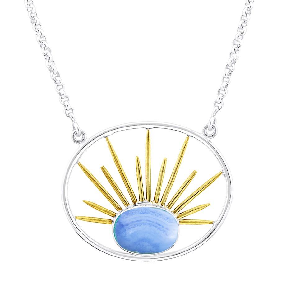 A silver necklace features a beautiful stone pendant. The Goddess Necklace Large in Various Gemstones by Gallardo & Blaine Designs is a circular silver frame with a blue gemstone at the bottom center, enhanced by gold vermeil spikes radiating from the gem