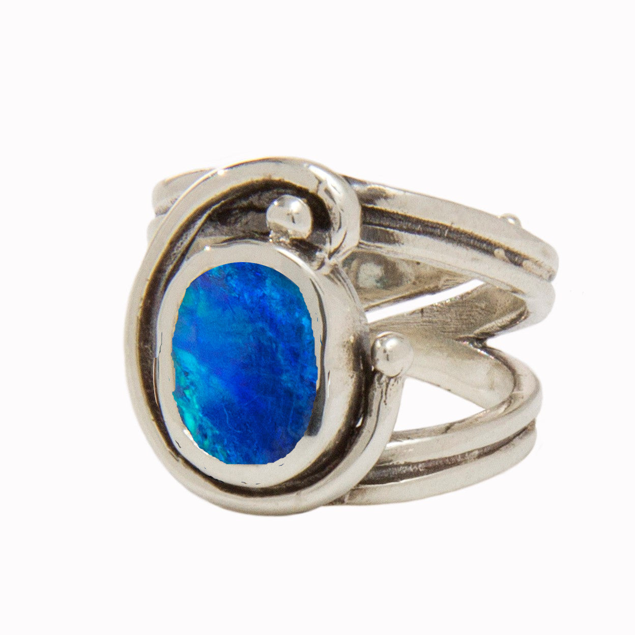 A Jasmine Ring in various gemstones by Gallardo & Blaine Designs featuring an intricate, swooping design which wraps around a vibrant oval blue gemstone at its center. The gemstones display tones of deep blue and lighter cyan, adding a striking contrast t