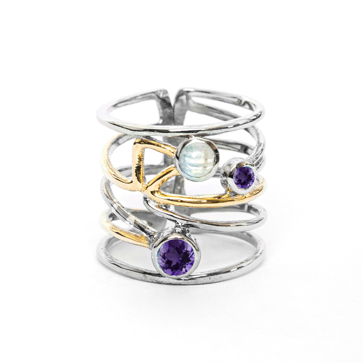 A stylish silver Lattice Ring in various gemstones by Gallardo & Blaine Designs featuring a contemporary, open band design with crisscrossing golden and silver bands. It is adorned with a blue moonstone and two purple gemstones, adding an elegant touch to