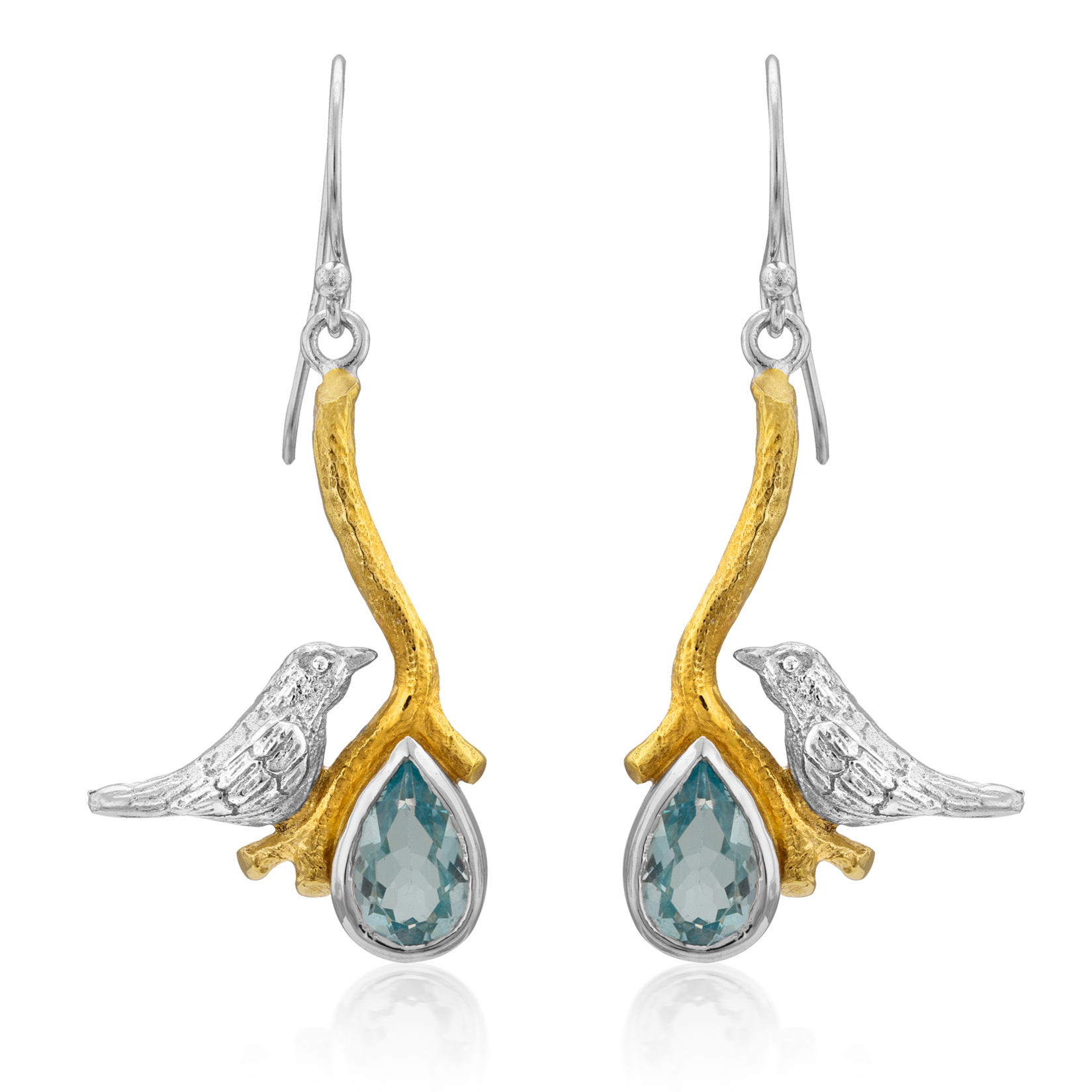 A pair of Lovebird Earrings in various gemstones by Gallardo & Blaine Designs featuring silver birds perched on gold-tone branches. Below each bird hangs a teardrop-shaped blue gemstone, creating elegant dangle drop earrings. The branches connect to silve