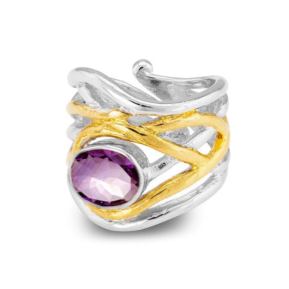 The Mayhem Ring in various gemstones by Gallardo & Blaine Designs with an intricate wavy design features a prominent gold accent wrapped around the band. The adjustable silver ring is set with a large, round, faceted purple gemstone in the center. The ove
