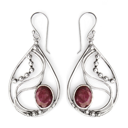 A pair of Gallardo & Blaine Designs Phoenix Earrings in various gemstones, teardrop-shaped and made of silver, featuring intricate swirling designs and small silver beads. Each earring boasts a large, oval, deep-red gemstone set at the base. These elegant