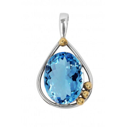 The Poppy Pendant Small in various gemstones, crafted in sterling silver by Gallardo & Blaine Designs, features a large, faceted blue gemstone at its center. This stunning piece has a teardrop-shaped frame adorned with three small gold beads on one side.