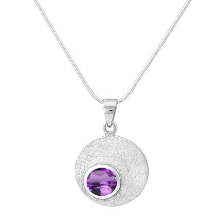 The Selene Necklace Silver - Small in various gemstones by Gallardo & Blaine Designs, crafted with a sterling silver chain, features a circular pendant. The pendant has a textured, silver surface and is adorned with a prominent round purple gemstone at it