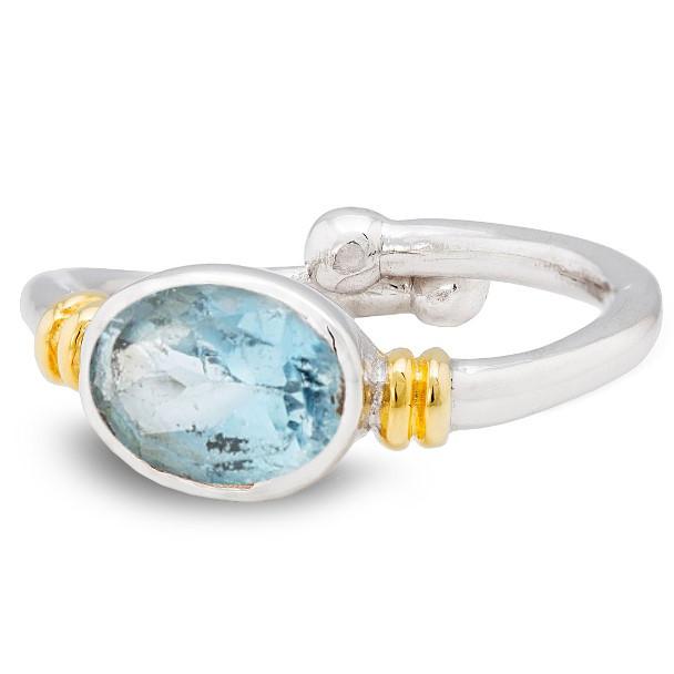 A Gallardo & Blaine Designs Senna Ring in various gemstones featuring an oval-shaped, blue gemstone as the centerpiece. The band has gold accents near the setting, adding contrast and elegance to the design. The adjustable ring has a stylish, modern look