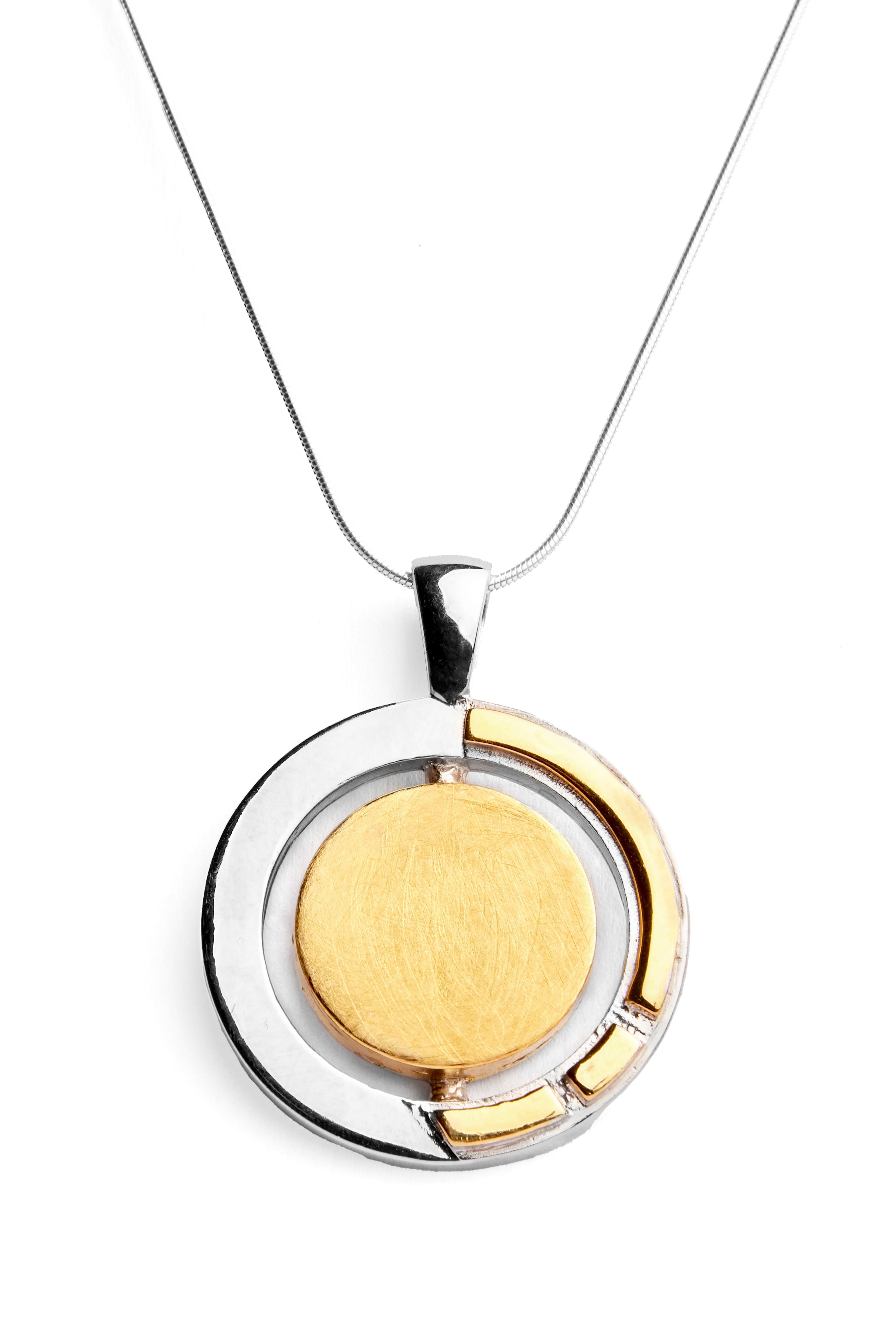 The Urú Large Pendant & Chain from Gallardo & Blaine Designs features a circular two-tone pendant, showcasing a sterling silver & gold vermeil outer ring with an Irish heritage jewelry-inspired inner circle. The Celtic pendant necklace hangs from a thin,
