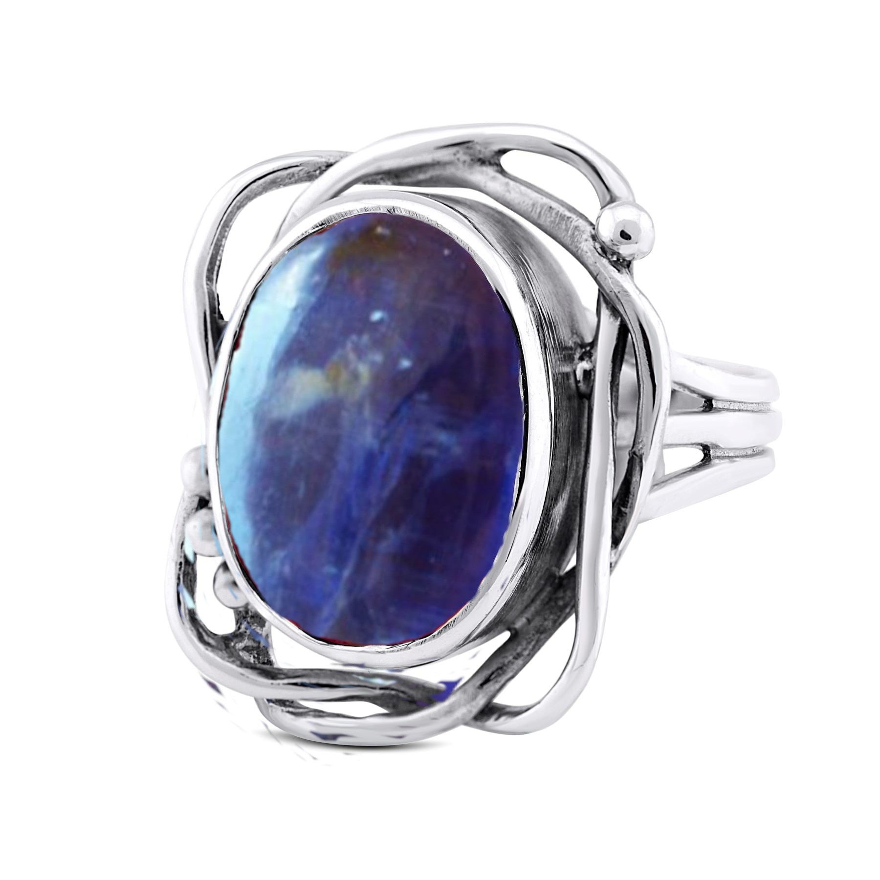 This Whirlpool Ring in various gemstones by Gallardo & Blaine Designs features an intricate design with intertwining bands and an oval-shaped blue gemstone in the center. The gemstone has varied shades of blue, giving it a unique appearance. The metalwork