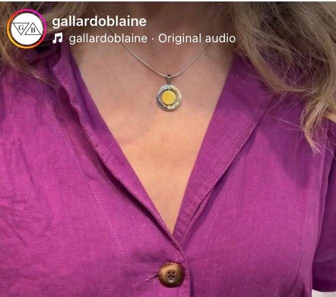 A person wearing a bright purple button-up shirt and the Gallardo & Blaine Designs Urú Small Pendant & Chain. The photo is cropped to show only the neck, collar, and upper chest area.