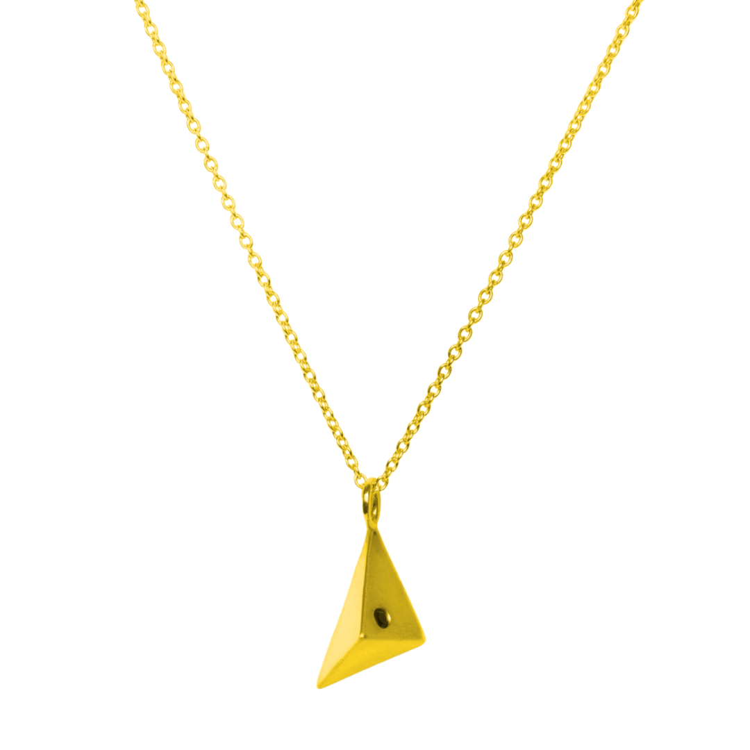 The Atria Pendant Necklace by Gallardo & Blaine Designs features a gold chain and geometric triangle pendant with a small black dot on one side, shown against a white background.
