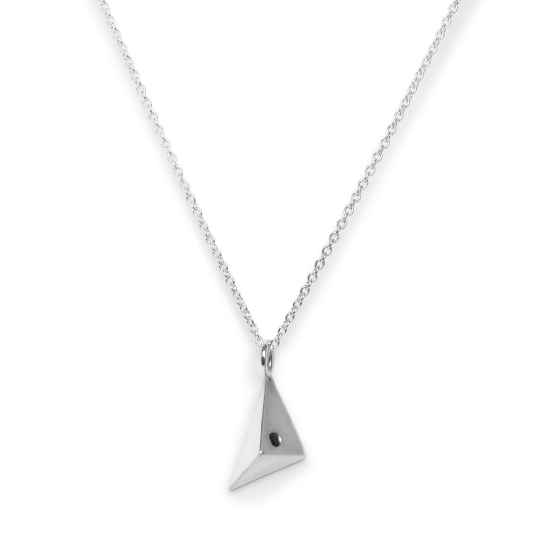 The Atria Pendant Necklace by Gallardo & Blaine Designs features a silver chain and a geometric pyramid pendant with a black dot accent, shown on a plain white background—ideal for anyone seeking a distinctive triangle necklace.