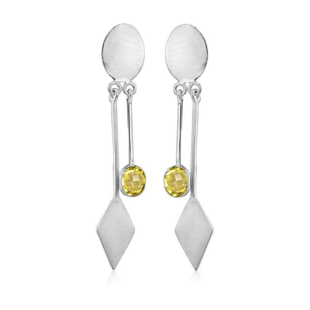 Gallardo & Blaine Designs' Karo Earrings feature modern elegance in silver with a yellow gemstone, hanging from an oval stud above two geometric shapes, including a diamond.