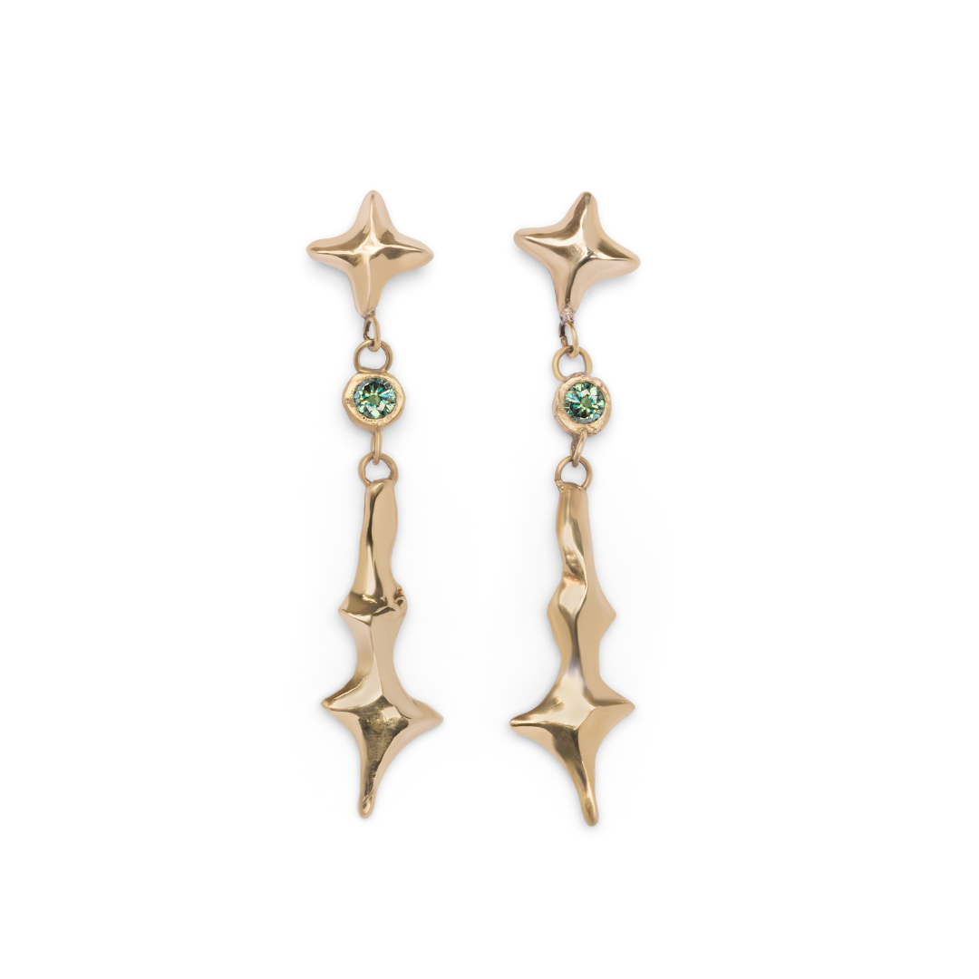 Nova Earrings Small with Moissanite by Madeleine Sculptural Jewellery, featuring star-shaped gold tops set with light green moissanite gemstones at the center and abstract, wavy lower pieces, displayed against a white background.