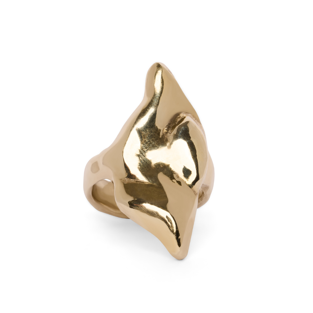 The Rift Ring by Madeleine Sculptural Jewellery is a gold ring featuring an abstract, shiny, and sculptural design that rises to a peak, evoking the look of a folded or flowing organic form.