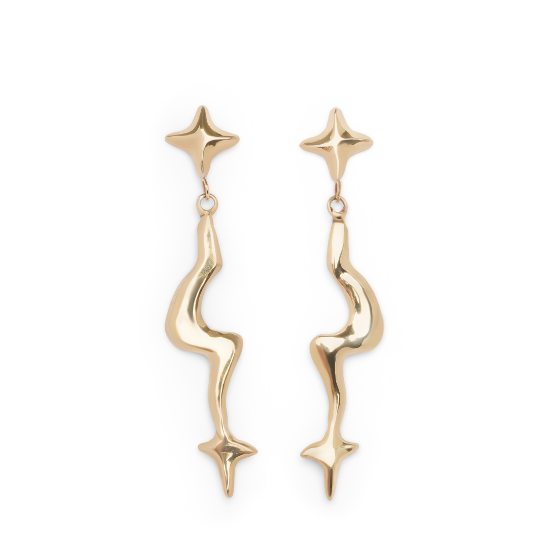 A pair of large, gold Nova earrings by Madeleine Blaine, featuring abstract wavy, elongated drops with star-like ends.