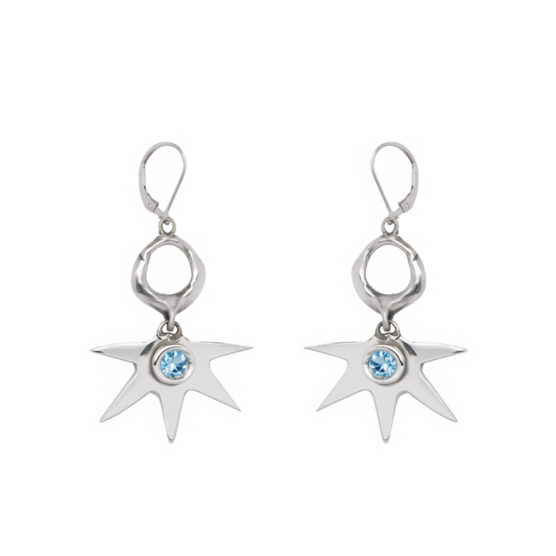 Madeleine Sculptural Jewellery’s Realta Earrings with 1 Moissanite feature silver, star-shaped drops with eight pointed rays radiating from a striking blue gemstone at the center and are finished with lever-back closures.