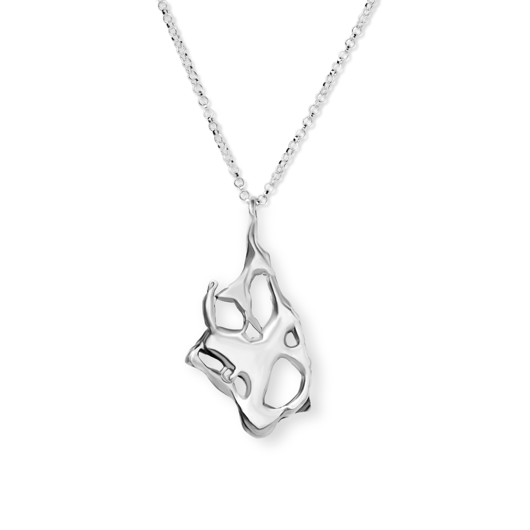 The Molten Necklace by Madeleine Blaine showcases a silver chain paired with an abstract, irregularly shaped pendant featuring open cut-out designs that evoke hand-carved artistry. Expertly crafted in Dublin, this eye-catching piece is beautifully present