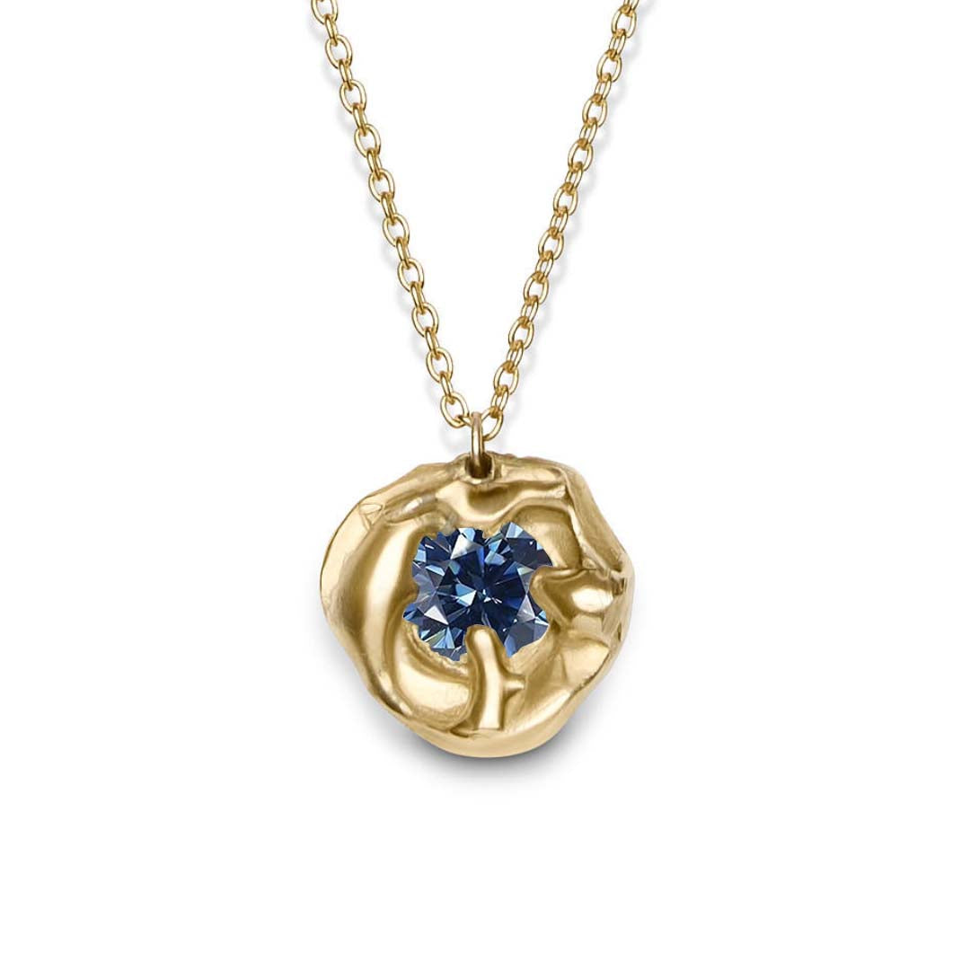 The Molten Necklace with Moissanite by Madeleine Sculptural Jewellery features an organic, hand-carved gold setting with a round moissanite gemstone at its center, suspended from a delicate gold chain.