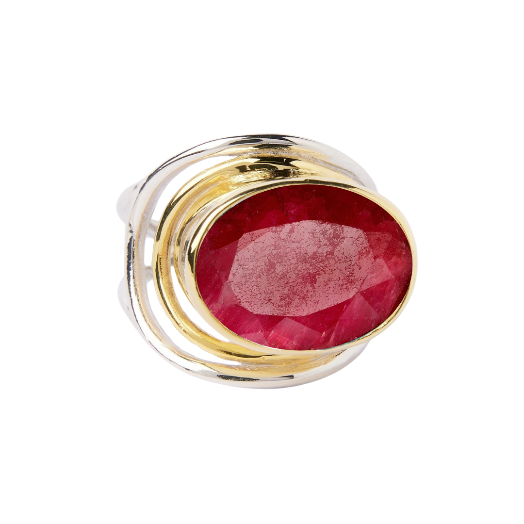The Party Ring by Gallardo & Blaine Designs is a bold gold accessory featuring a large multifaceted oval red gemstone, with an adjustable swirling band that elegantly frames the stone.