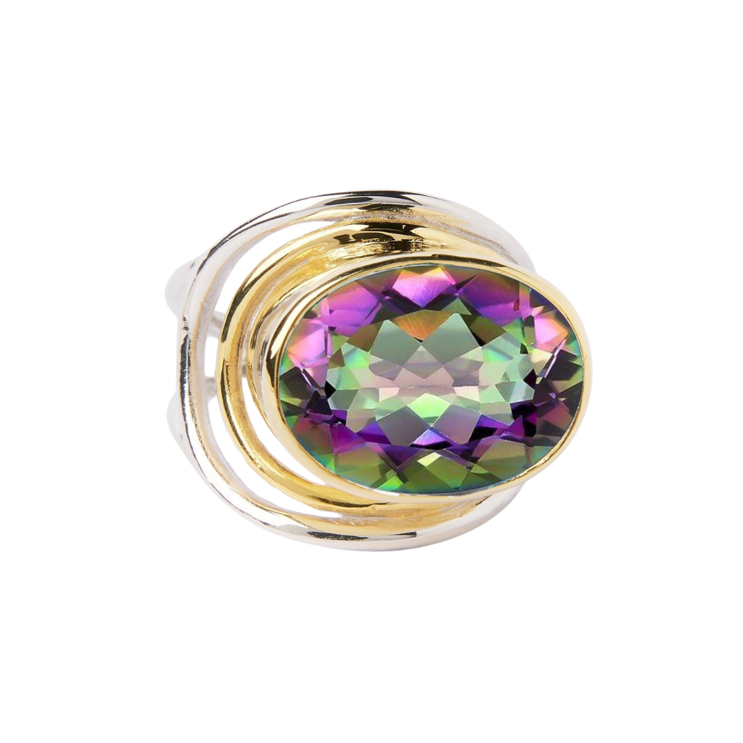 The Party Ring by Gallardo & Blaine Designs features a stunning gold statement design with a large faceted multicolored gemstone showcasing green, purple, and pink hues. Its elegant swirling design makes it the perfect modern standout piece.