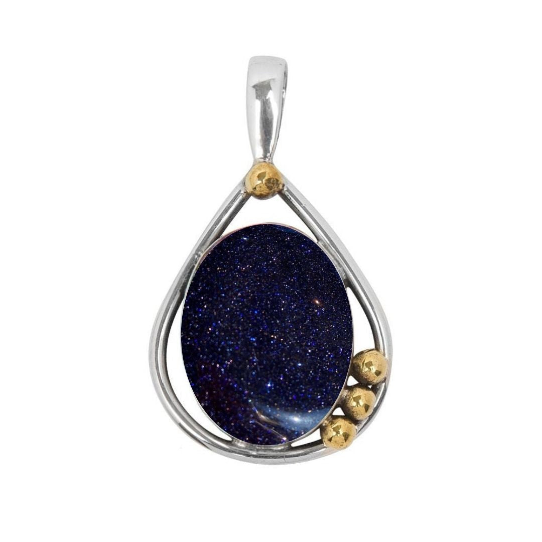 The Poppy Pendant Small by Gallardo & Blaine Designs showcases a teardrop-shaped sterling silver and gold frame with an oval blue gemstone, highlighted by three petite gold spheres on the silver setting.