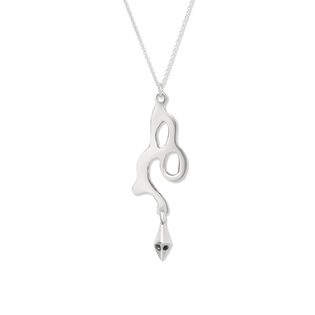 Discover the Madeleine Blaine Serpent Pendant—a silver necklace showcasing an abstract, fluid serpent pendant with an open loop design, finished with a small geometric charm adorned by two tiny black stones. Reminiscent of hand-carved Celtic jewelry, this