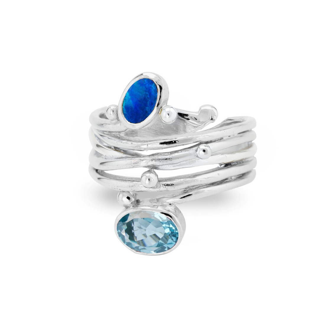 Gallardo & Blaine Designs’ Snake Ring in Silver features adjustable overlapping bands, a round blue opal atop an oval light blue gemstone, all accented with small silver beads.