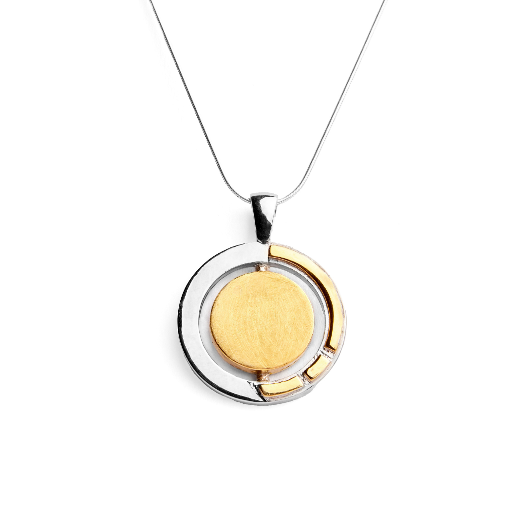 The Urú Large Pendant & Chain by Gallardo & Blaine Designs features a striking silver necklace with a circular Celtic pendant, a large central gold disk, and an asymmetrical silver and gold border on a fine silver chain.