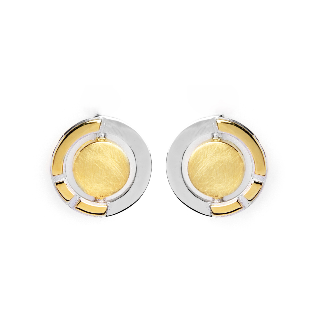 The Urú Studs by Gallardo & Blaine Designs feature round Celtic-inspired earrings with a central gold-toned circle, sterling silver outer ring, and geometric gold accents—a timeless nod to classic Irish jewellery, shown on a white background.