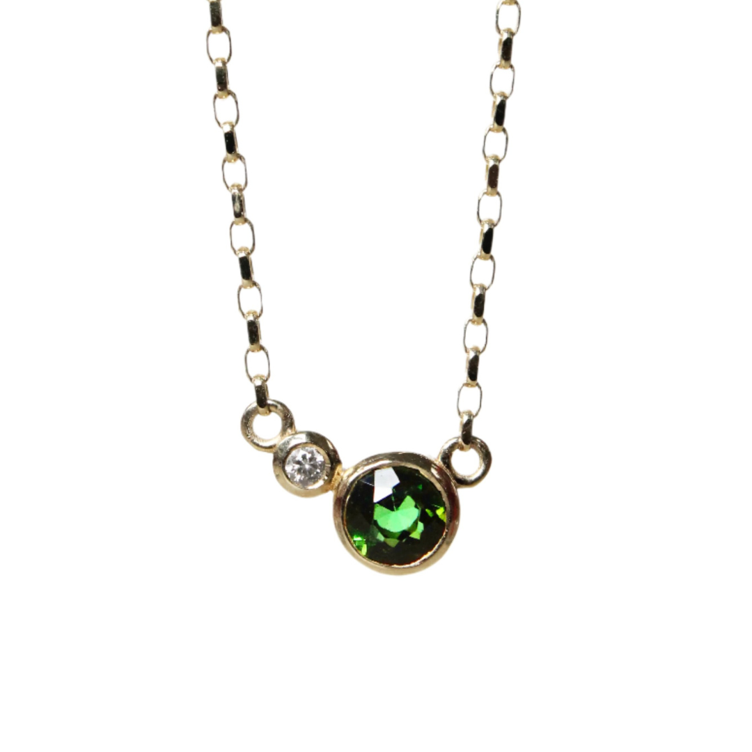 The Verdant Embrace 9ct Yellow Gold Necklace by Madeleine Fine Jewellery features a small lab-grown diamond and a larger green tourmaline pendant set side by side in gold bezels on a rectangular-link chain. Shown on a white background.